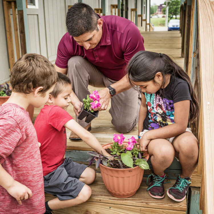 teacher-teaching-three-children-how-to-plant-flowers