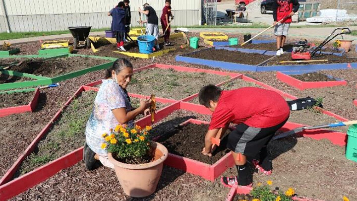 Elder and teacher Delberta Frazier sows traditional plants with students in the Umonhon Nation Public School garden.